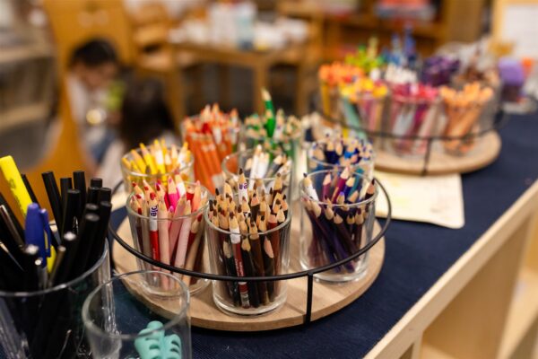 Freshly sharpened colored pencils are sorted into glass jars on trays in an Innovations Academy classroom.