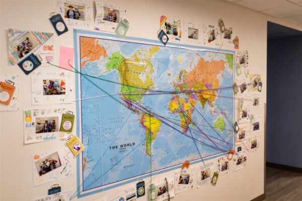 A photo of a world map with strings and push pins connecting and overlapping, highlighting a global project.