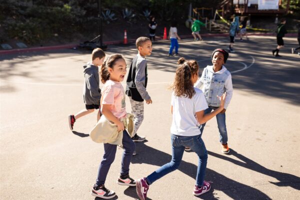 Innovations Academy students run on a blacktop outside in a group.