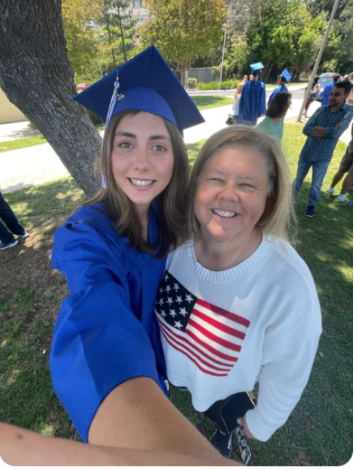 Innovations Academy teacher and director, Lisa Smith stands with a high school graduate in a blue cap and gown, both smiling at camera.