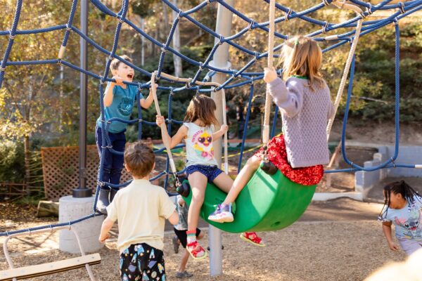 Students play and run around an outdoor playground on Innovations Academy campus.
