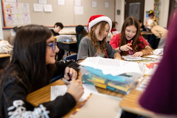Students at Innovations Academy are working at a table together in a classroom.